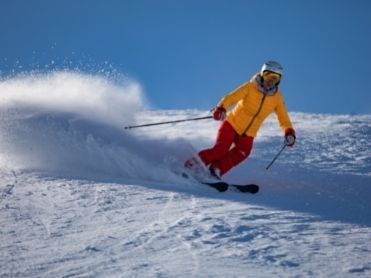 Skier op piste gele jas
