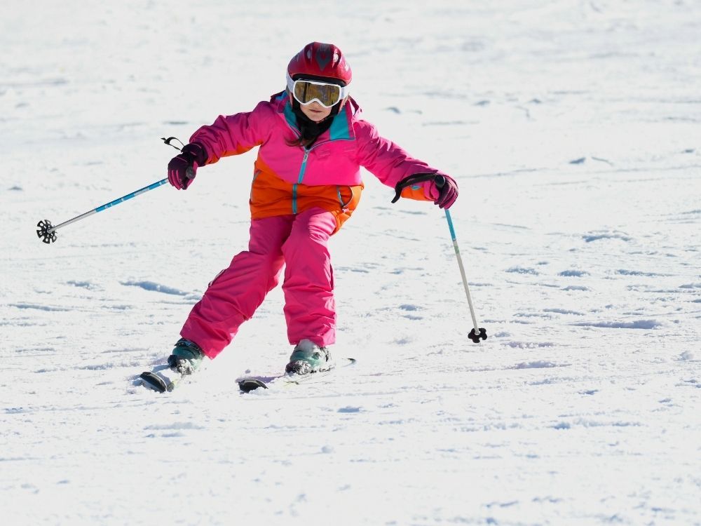 wintersport meisje in roze skipak op ski's